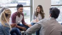 In therapy, a teen boy shares life experiences with group.